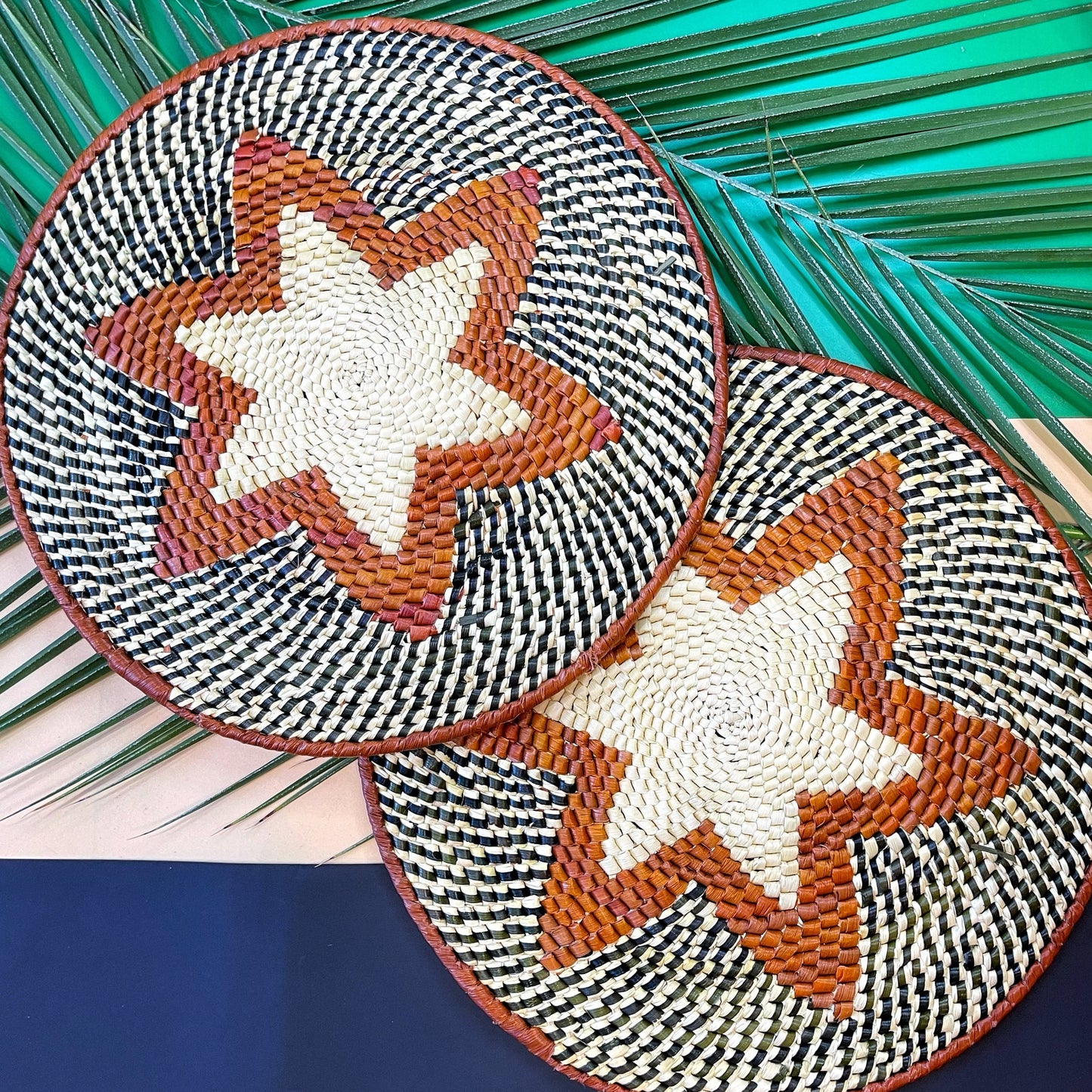 Handcrafted tucuma placemats with black and white houndstooth and central tan stars on a backdrop of palm fronds.