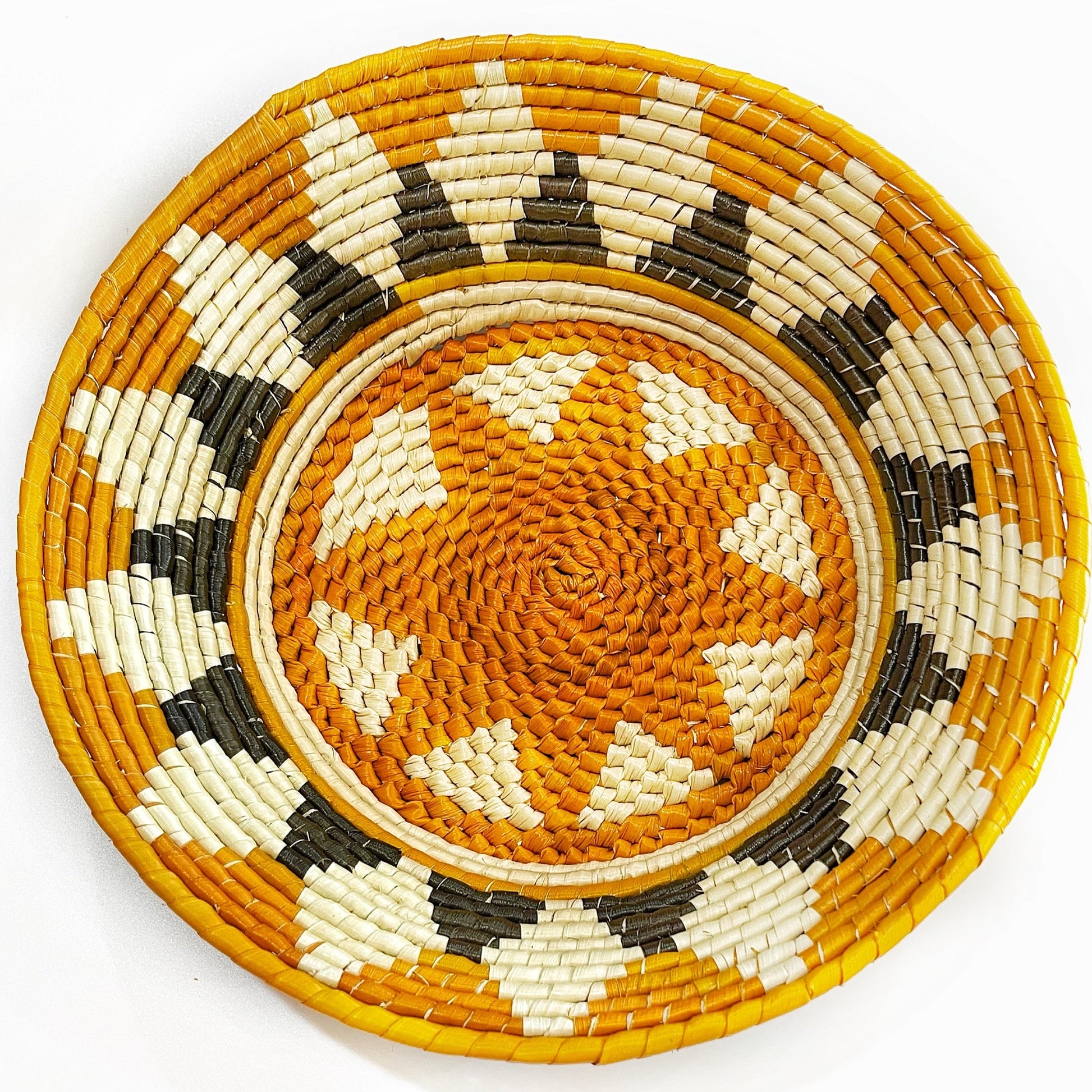 The bowl features a striking pattern, combining hues of natural tan, creamy white, and dark brown or black. The design radiates from the center, creating a sense of movement and intricacy