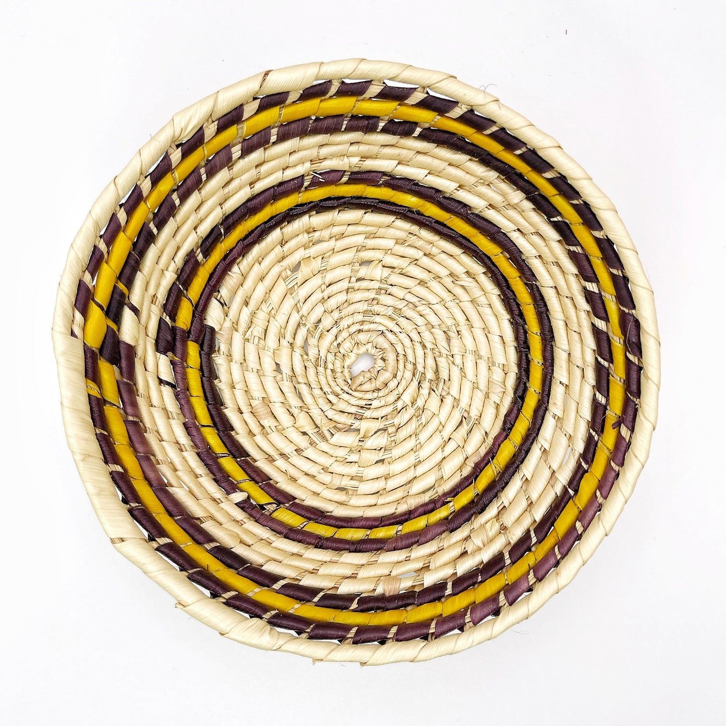 The bowl features concentric circles in beige, accented with bands of purple, and yellow, showcasing the intricate handwoven pattern.