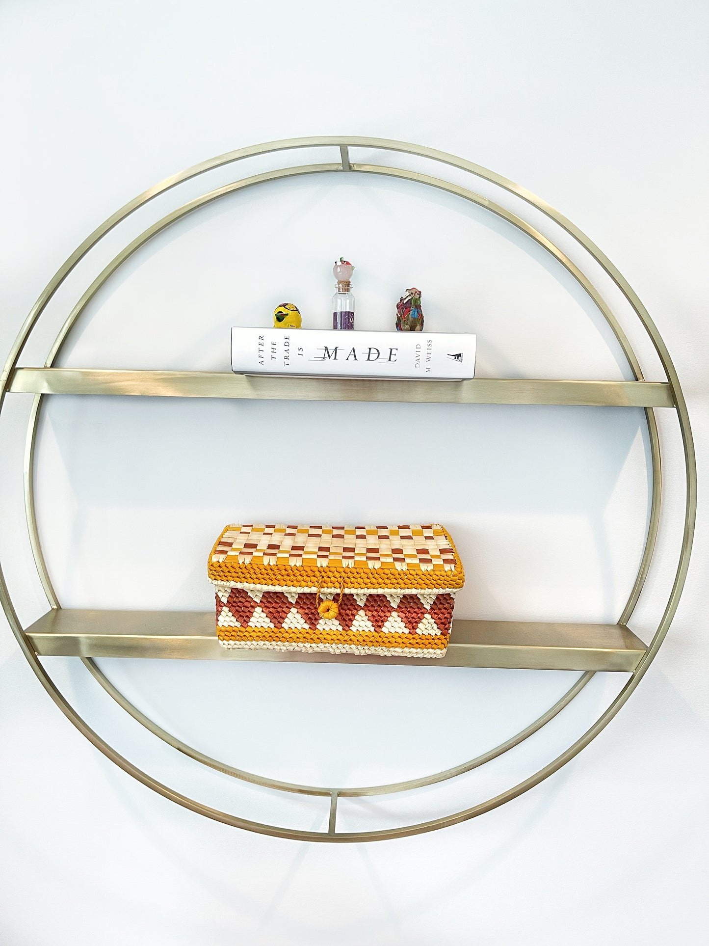 Chic, handwoven tucuma box in yellow, white, and maroon, displayed on a modern circular metal shelf, adding a touch of artisanal flair to the decor.