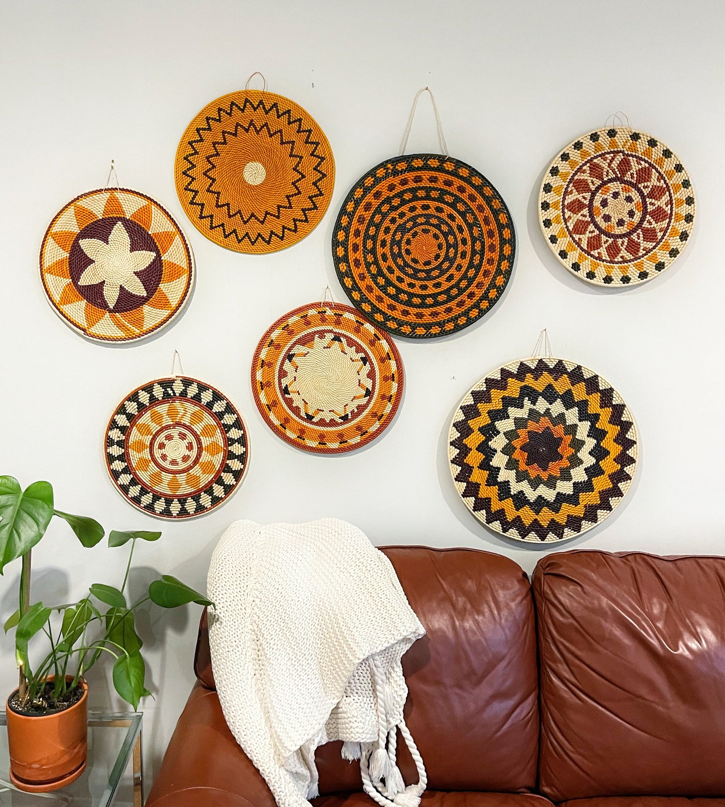 a wall, showcasing intricate craftsmanship from the Amazon rainforest region. Each mandala has a unique pattern and color scheme, predominantly in earthy tones of orange, brown, and cream, embodying the natural palette of the rainforest.