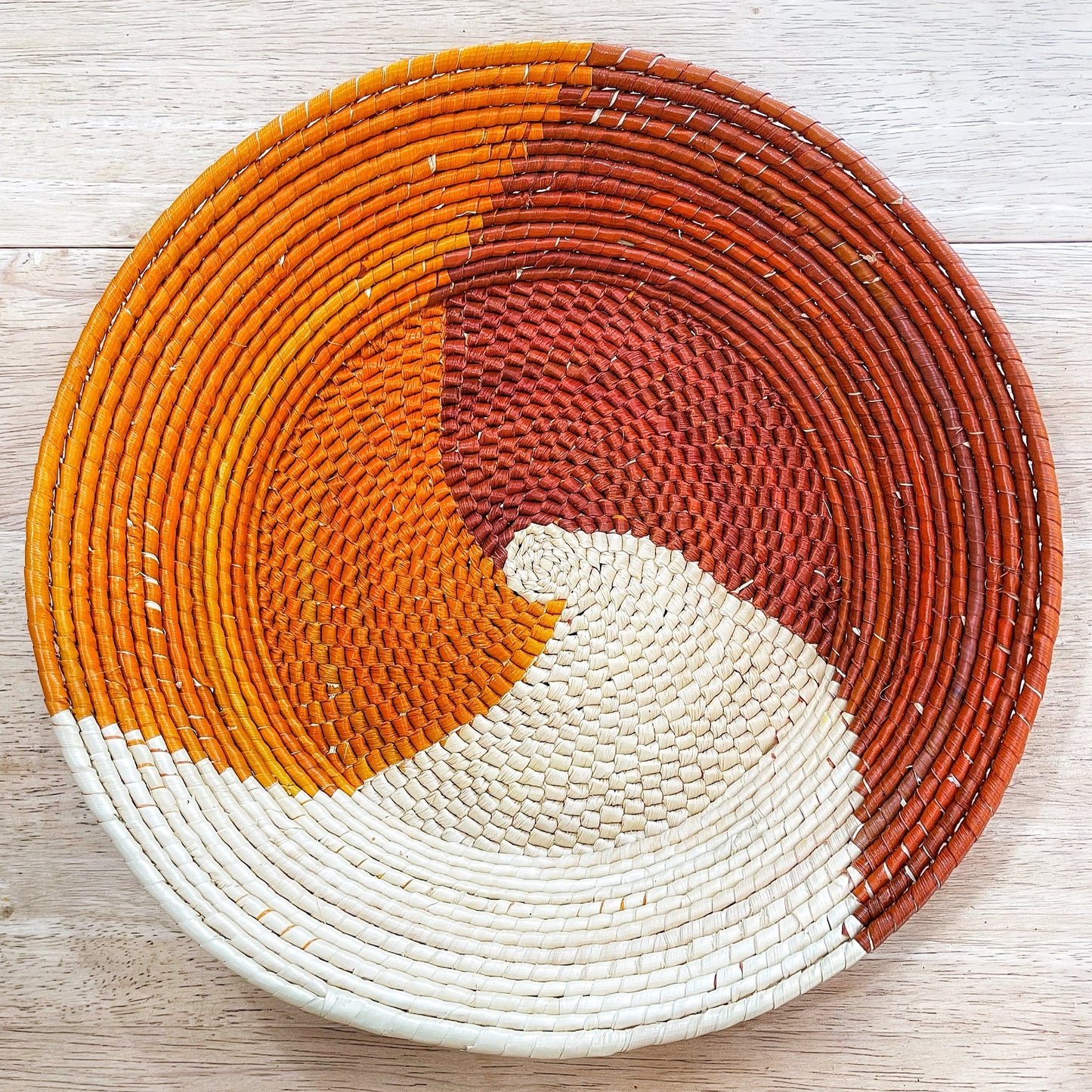 Round handwoven Amazonian bowl made from tucuma palm fibers. Features a geometric dark brown and white starburst pattern in the center, with a natural brown rim.