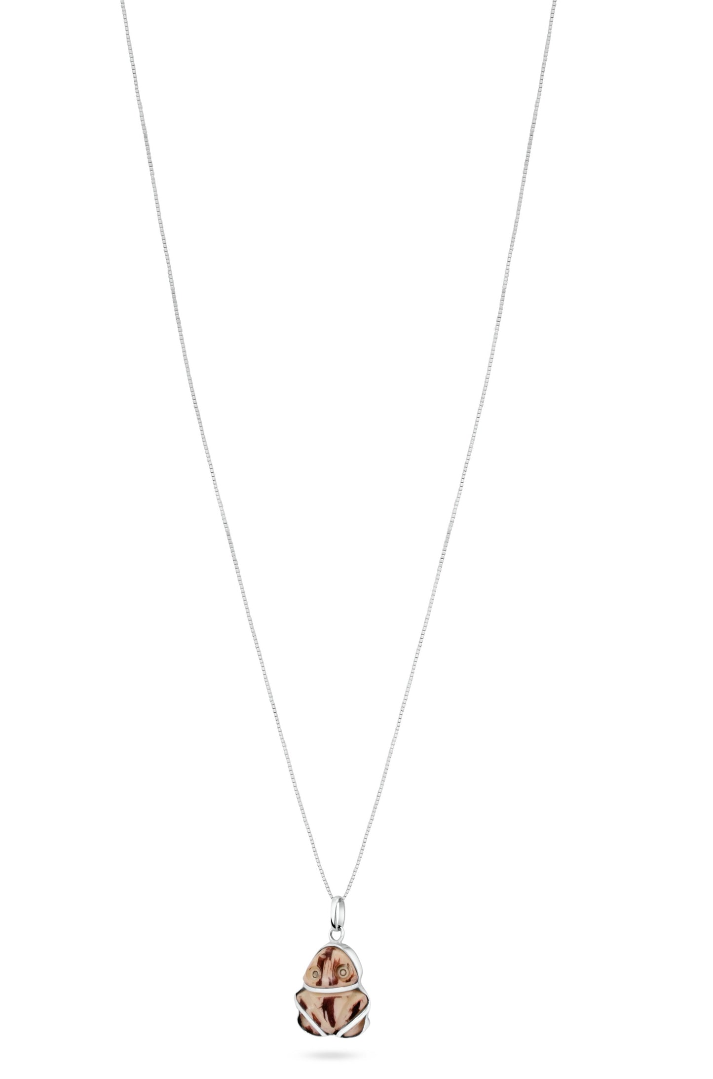 A silver chain with a Muiraquitã pendant crafted from Jarina seed, resembling eco-friendly ivory with symbolic engravings, evoking the Amazon's essence.