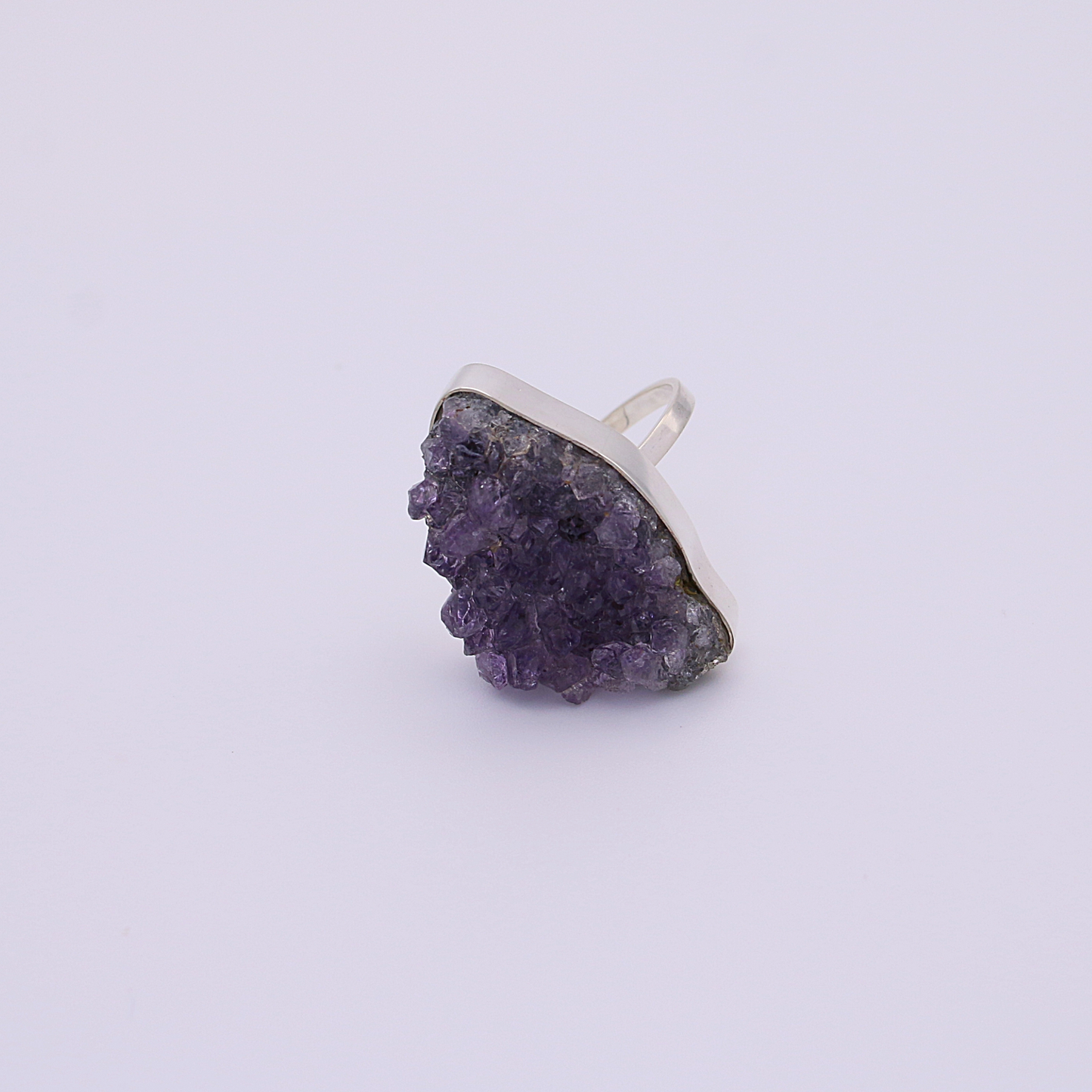 A single raw amethyst ring on a white background, capturing the natural light.