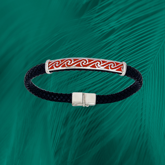 Braided black leather bracelet in red with a sterling silver wave motif in the center and a simple silver clasp, presented against a rich, feathered emerald green background.