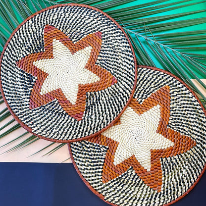  Handcrafted tucuma placemats with black and white houndstooth and central tan stars on a backdrop of palm fronds.