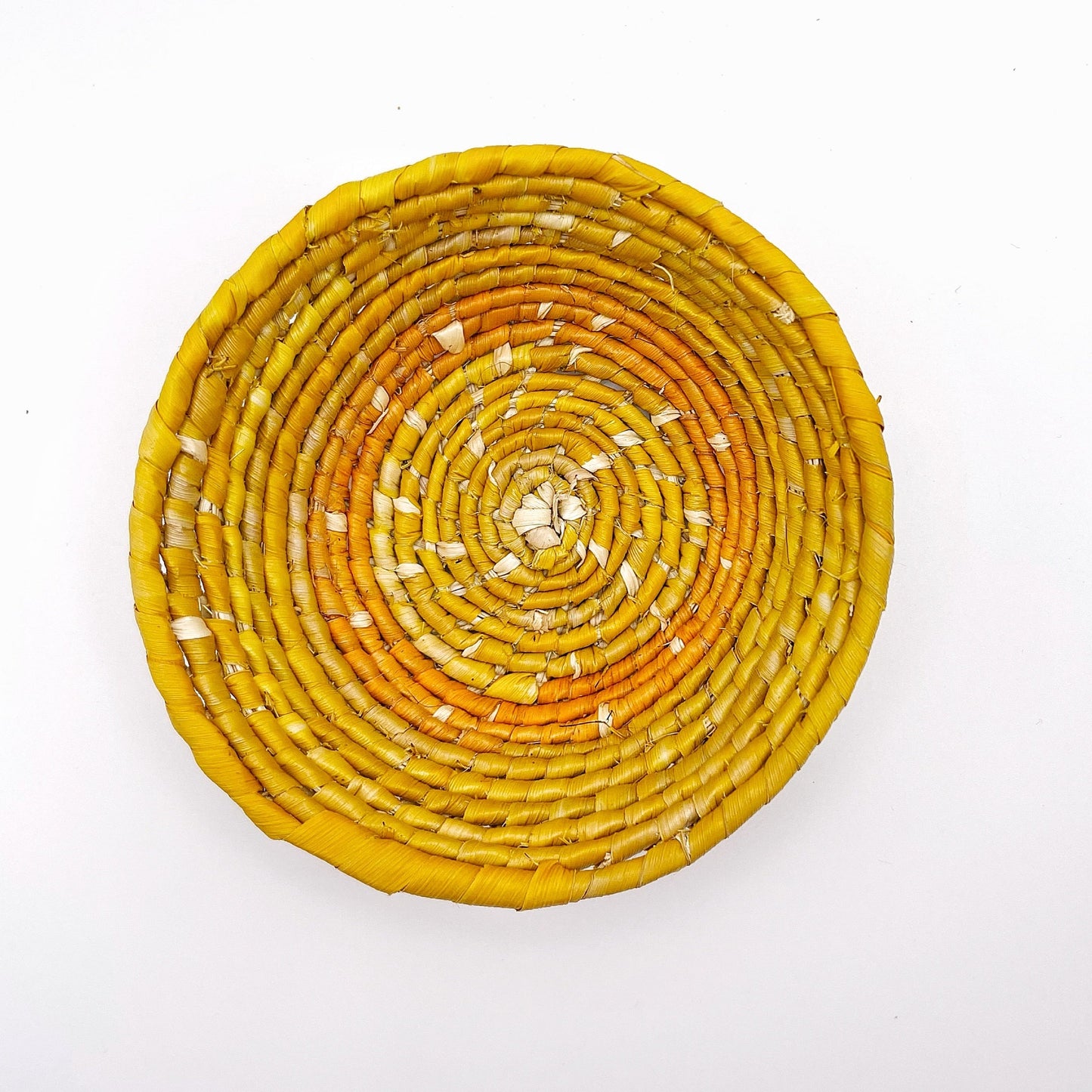 The woven bowl features a gradient of colors from a light beige center to varying shades of yellow, culminating in a deep orange rim, in a spiraling design.