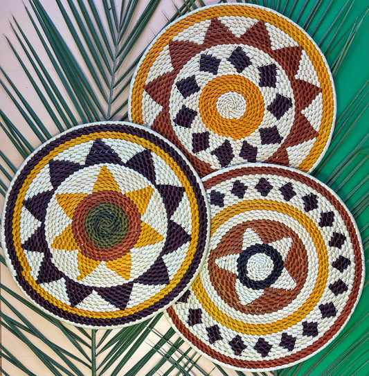 Three handwoven Amazonian placemats: natural, brown, yellow, green & black. Geometric patterns with stripes, diamonds & central star.