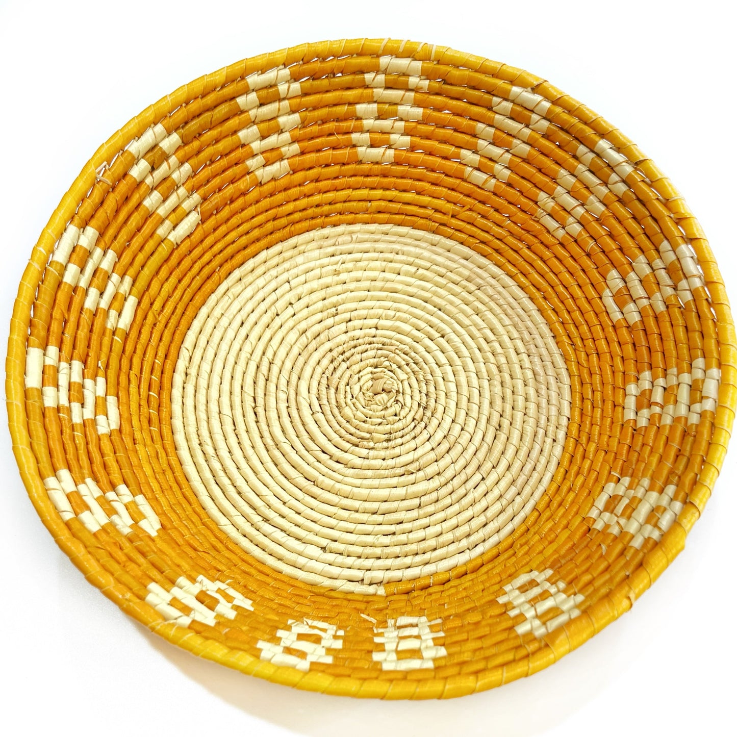 Artisanal tucuma bowl with a creamy spiral center, encircled by a vibrant yellow border with white cross-stitch patterns.