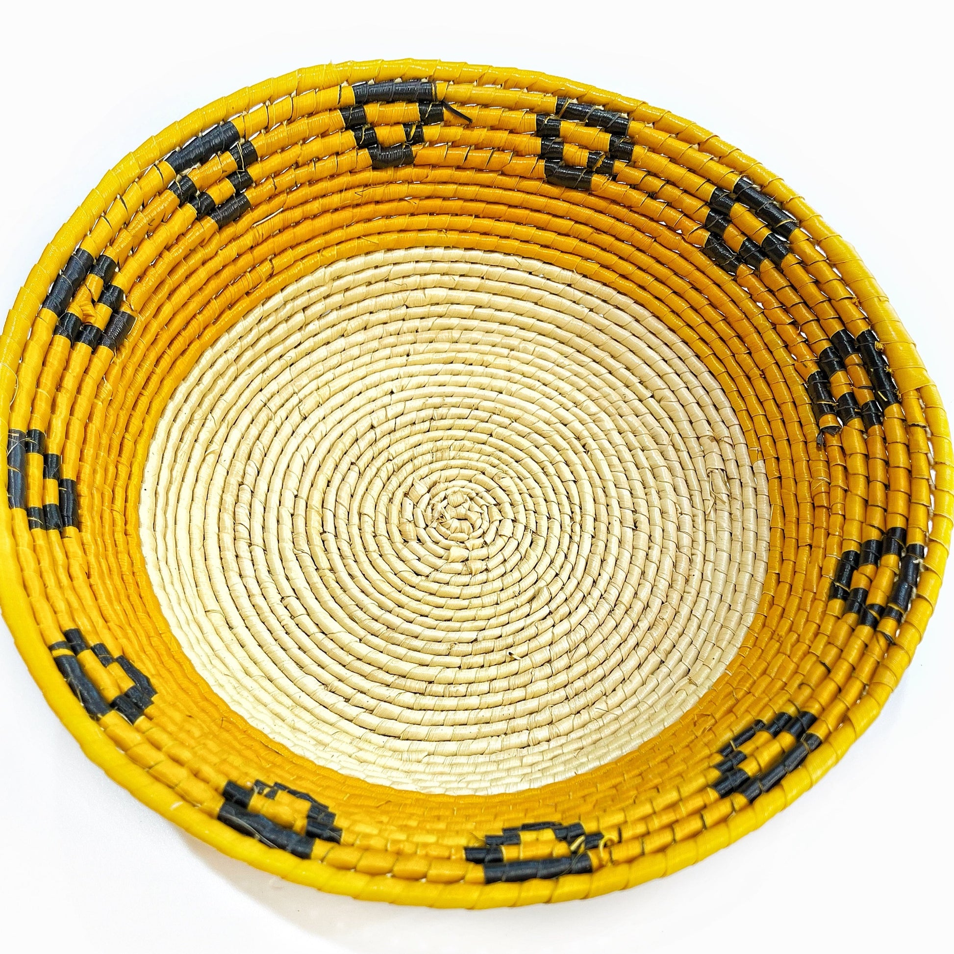 A tucuma fiber bowl with a natural cream center, a bold yellow rim, and black geometric details.