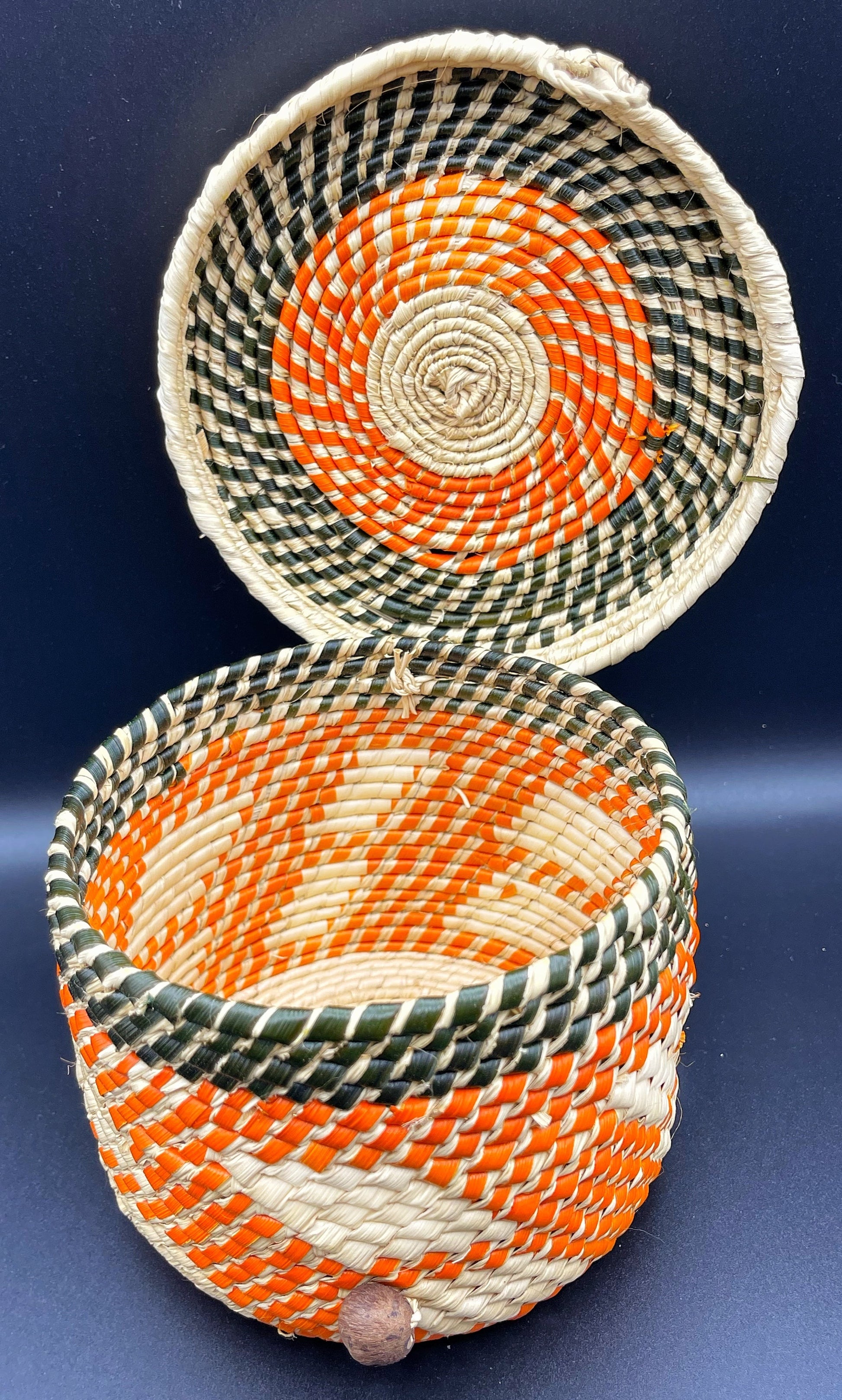 Open handwoven tucuma palm box with intricate orange, white, and black patterns, revealing the detailed craftsmanship inside and out