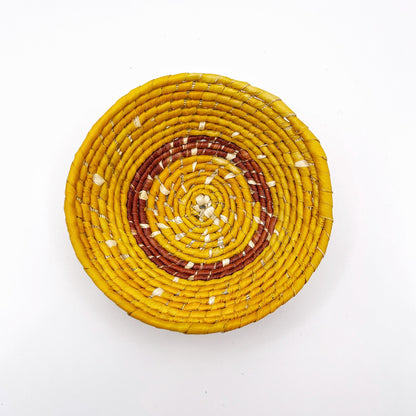 The bowl displays a spiraling pattern with a light beige center transitioning through shades of yellow to a warm, reddish-brown perimeter.