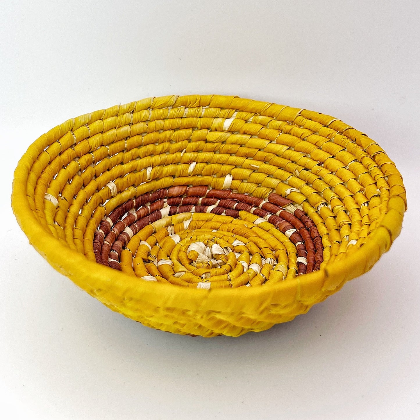 The bowl shows a beautiful coiled pattern in shades of yellow, transitioning to deeper orange hues, with a striking yellow rim.