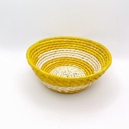 Handwoven Amazonian trinket bowl: natural cream interior, vibrant yellow rim. Intricate coil weave pattern. Made from tucuma palm fibers.