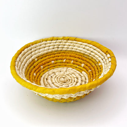 Handwoven trinket bowl made from tucuma palm fibers. Natural cream interior, vibrant yellow rim. Intricate coiled weave pattern.