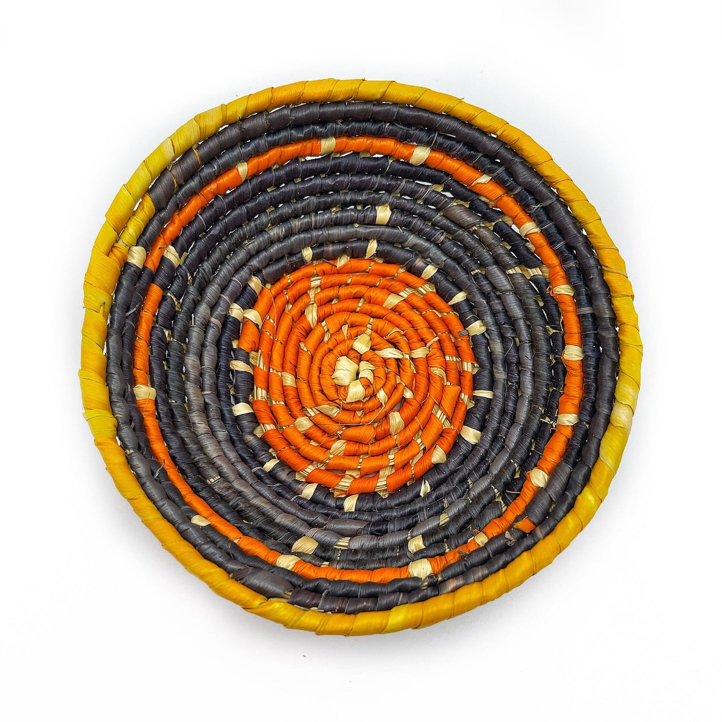 The bowl has a concentric design with beige at the center, surrounded by layers of orange and black, and a bright yellow outer rim, all woven in a spiral pattern.