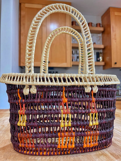 small/medium-sized handwoven Tucuma palm basket with a sturdy structure, featuring a rich blend of natural cream and deep brown fibers, accented with vibrant orange and yellow patterns.