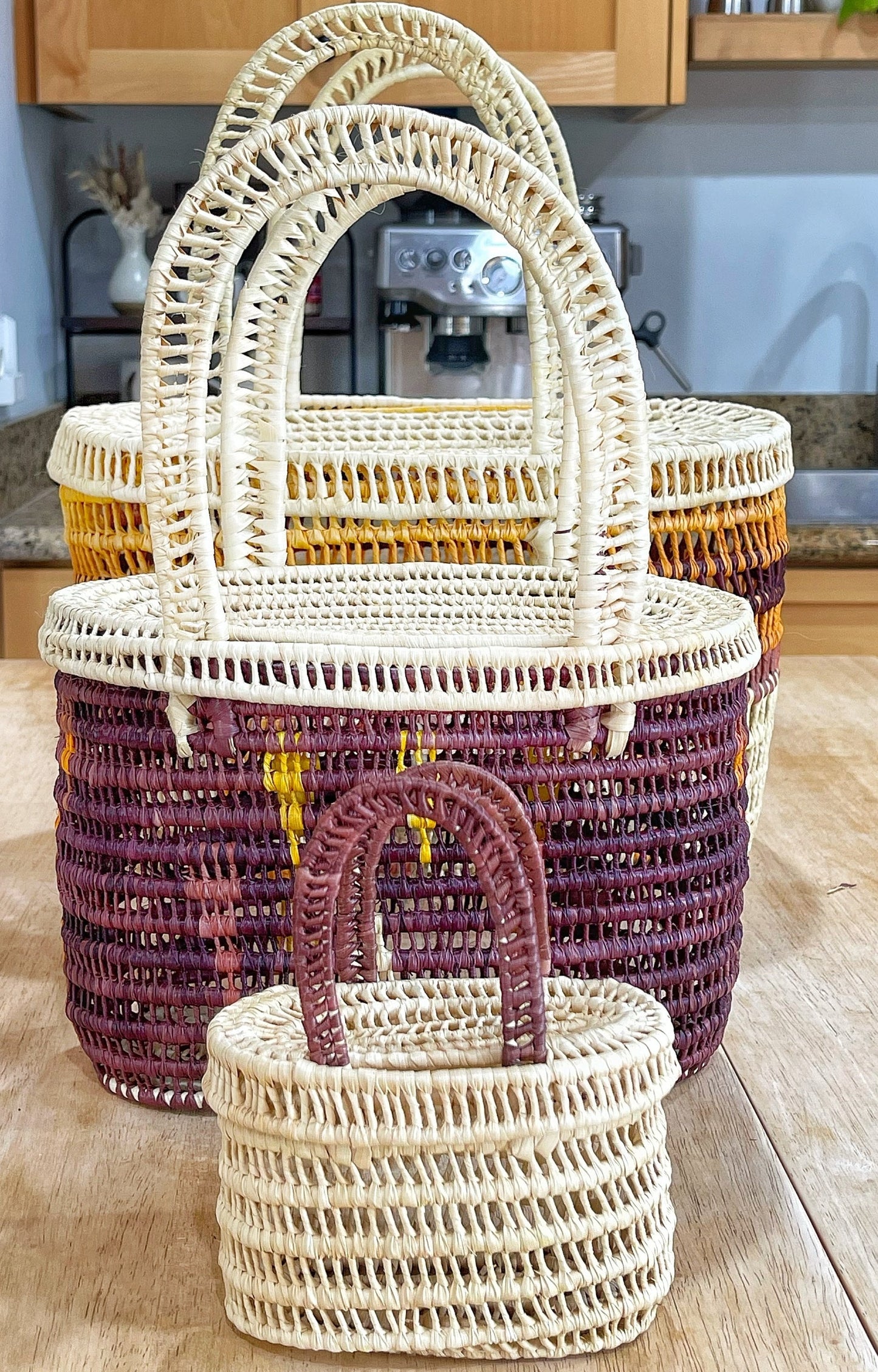 Three handwoven baskets on a kitchen countertop: the largest stands tall with double handles, contrasting the petite mini basket in the front.