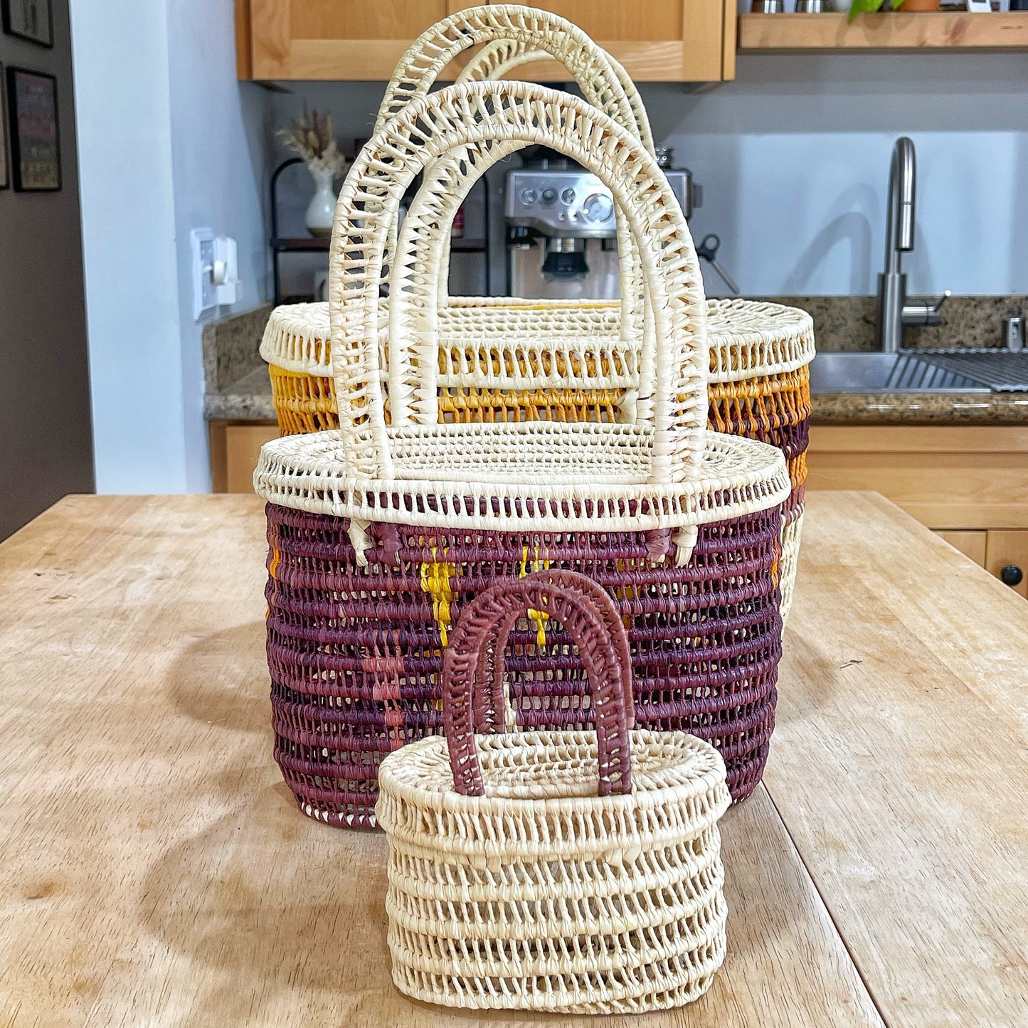 Three handwoven Tucuma palm baskets from Brazil displayed in ascending sizes: mini, small, and medium. They feature strong natural fibers in cream and brown, showcasing traditional craftsmanship and durability