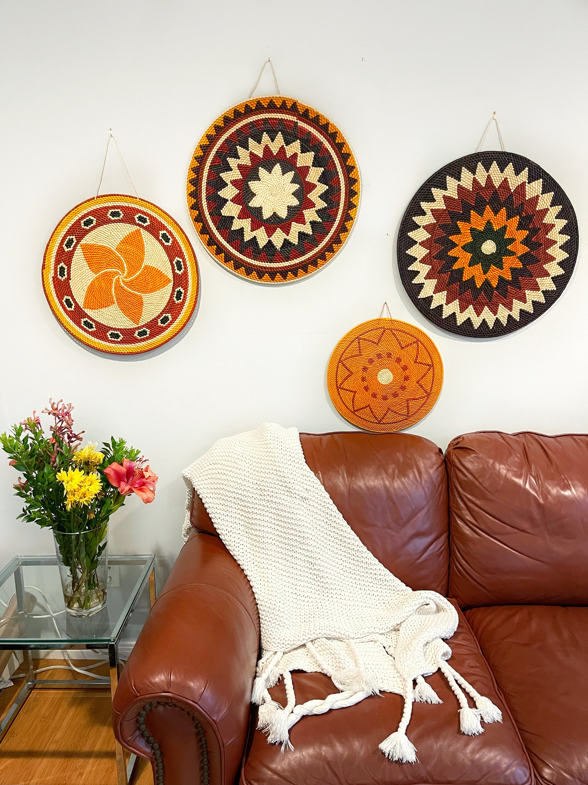 In the living room, mandala walls art piece features a symmetrical pattern in warm tones of cream, orange, and brown, adding depth and tranquility to the space.