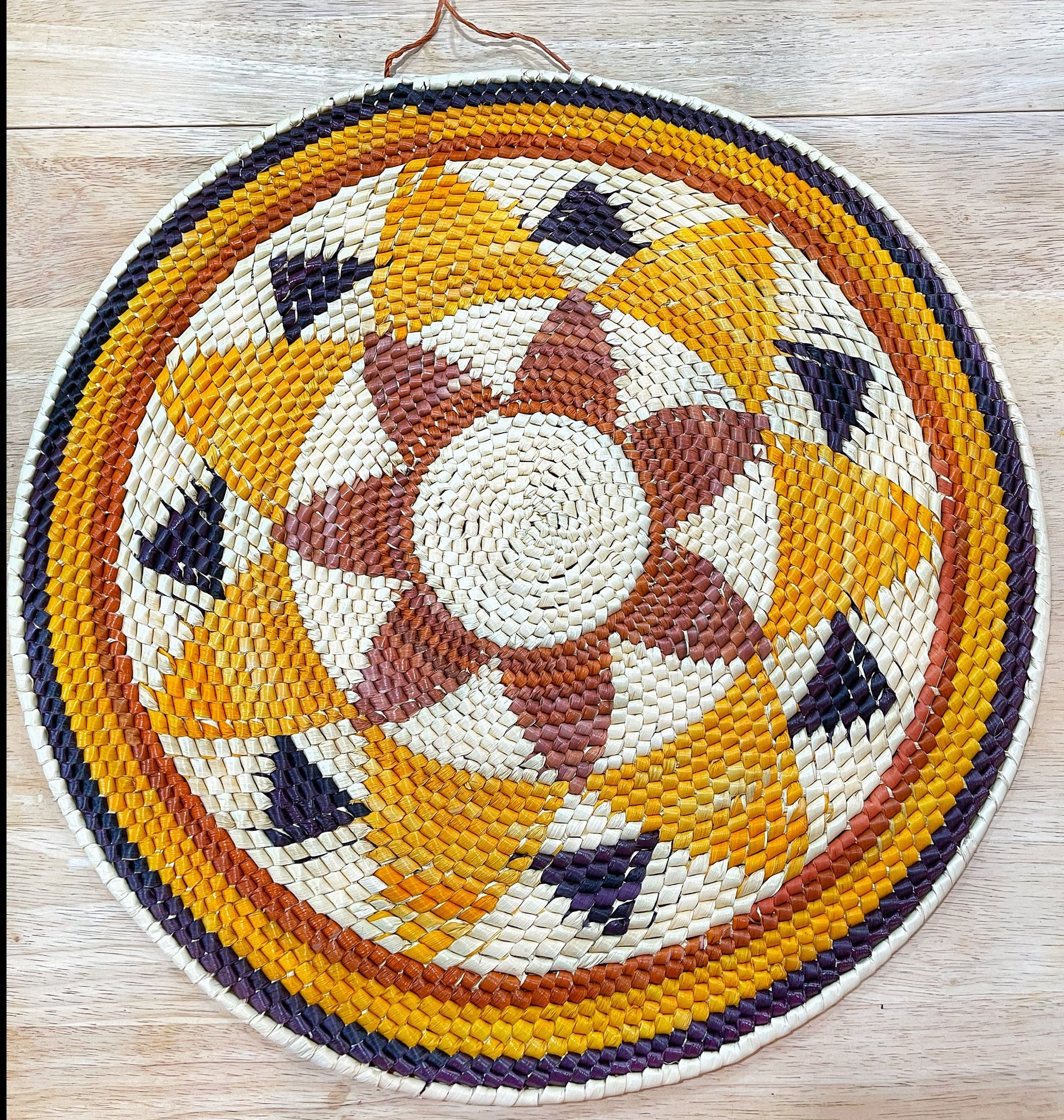 Handwoven Amazonian mandala wall art in natural fibers. Colorful geometric design adds a touch of bohemian style and supports rainforest artisans.