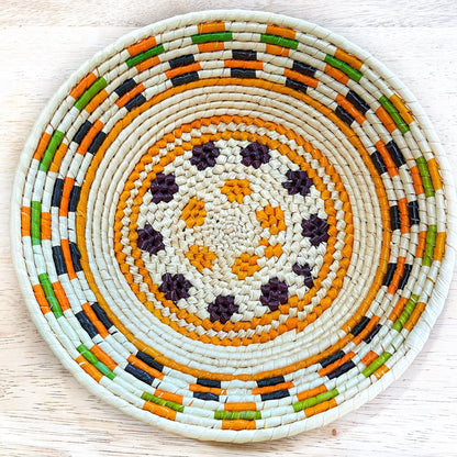 bowl with cream spirals, a vibrant striped rim in orange, green, black, and a central starburst pattern.