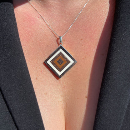 Silver square pendant with Amazonian seed marquetry in brown hues from babassu and coconut, creating a concentric, natural-toned design.