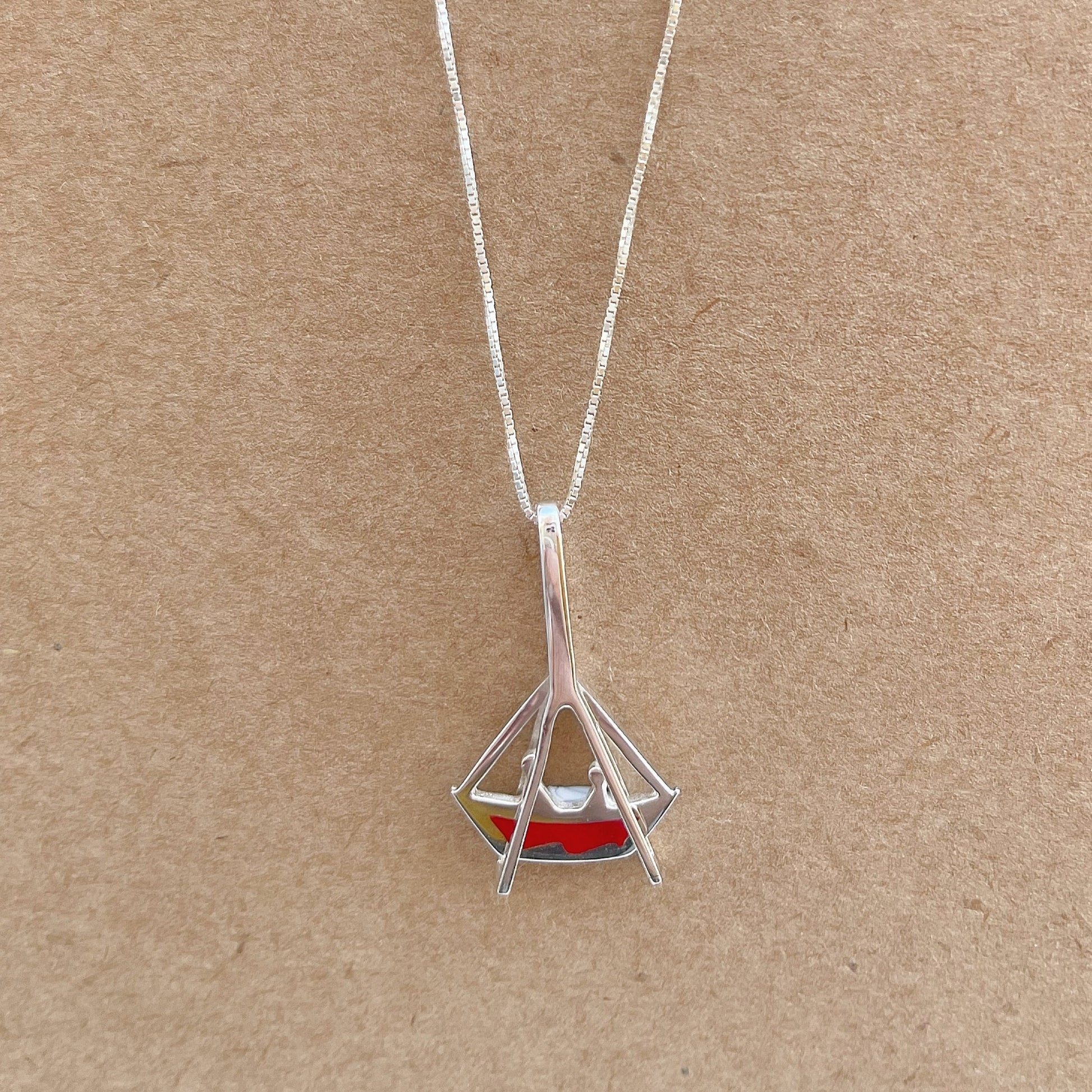 A .925 sterling silver necklace with a boat-shaped pendant, featuring a glossy red inlay. The design evokes the festive spirit of a Brazilian celebration and the whimsical charm of a classic amusement ride