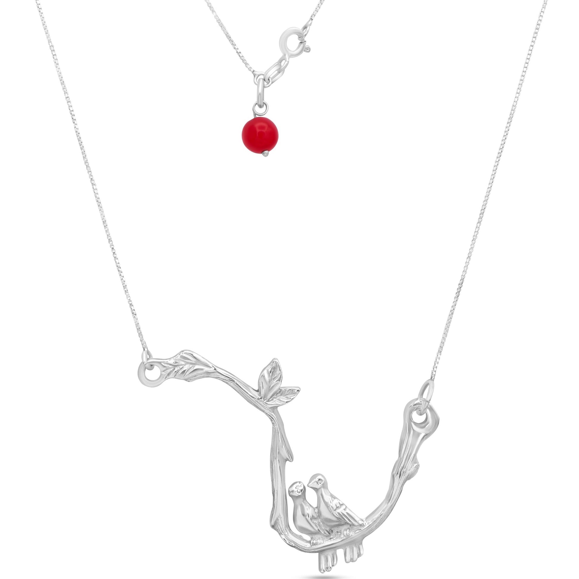 A sterling silver necklace with a pendant of two intertwined doves and a bright red agate bead, symbolizing love and harmony.