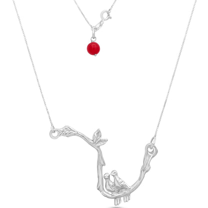 A sterling silver necklace with a pendant of two intertwined doves and a bright red agate bead, symbolizing love and harmony.