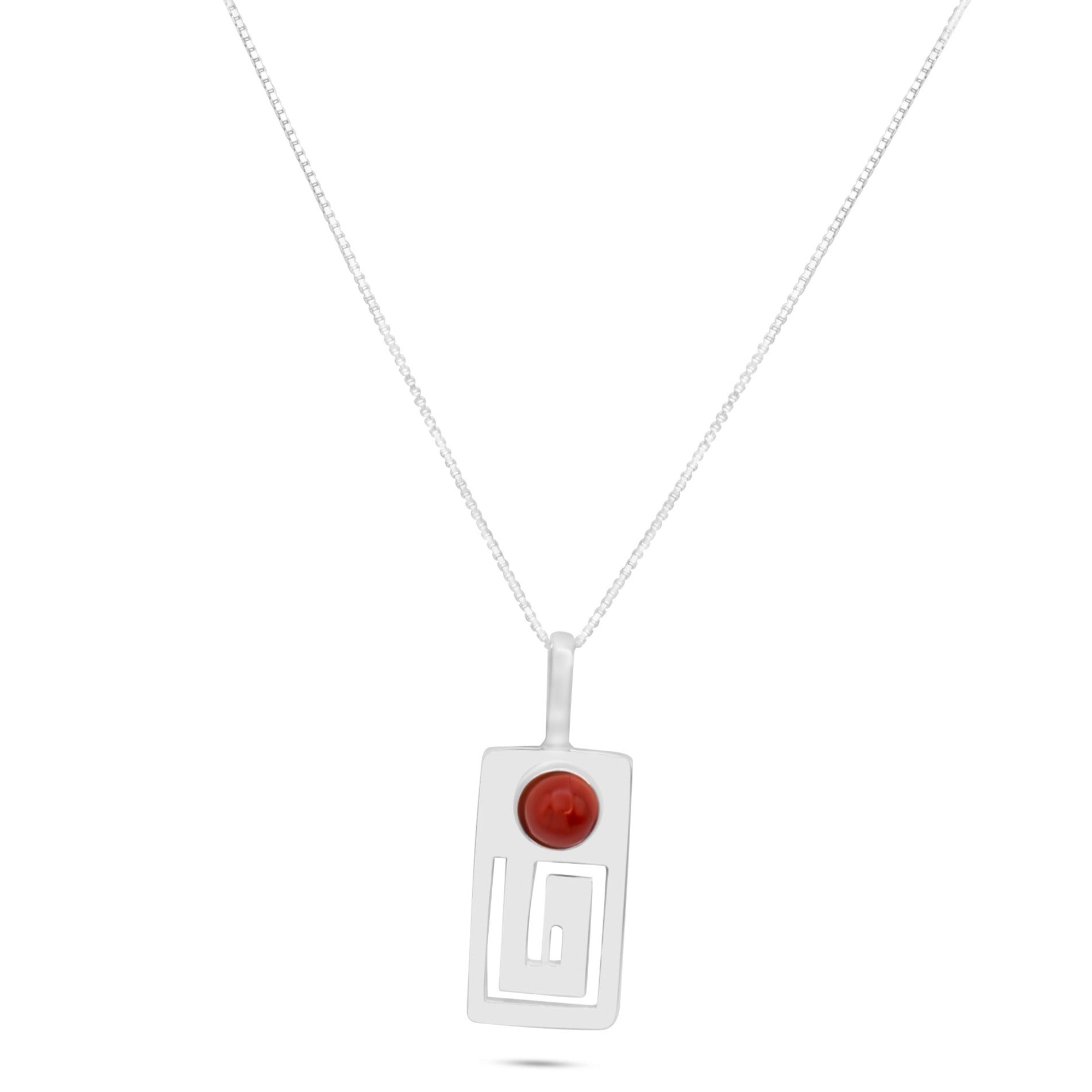 A handmade .950 sterling silver pendant with a red jasper gemstone, inspired by Marajoara civilization's ancient Amazonian art, features geometric cut-outs and hangs on a delicate chain.