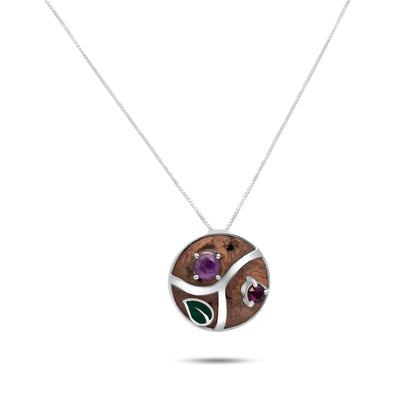 A circular, handcrafted necklace pendant made of Brazil nut material, featuring a unique design with inlaid natural amethyst and garnet stones on a silver chain.