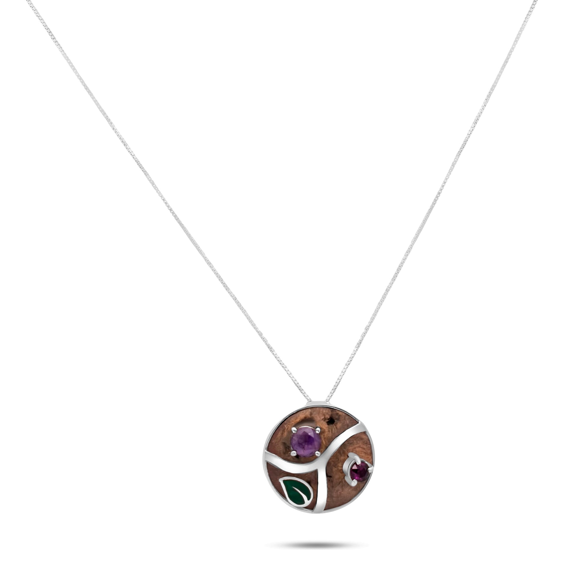 A handcrafted necklace pendant with a Brazil nut base, adorned with amethyst and garnet stones set in a swirling silver design, suspended on a delicate chain.