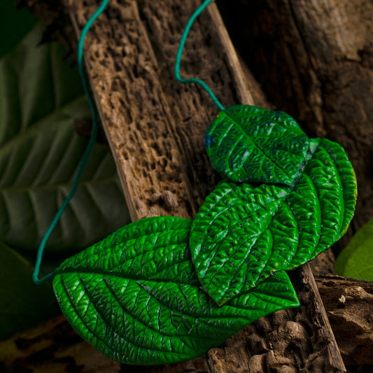 Realistic leaf necklace. Handcrafted from natural rubber & açaí seed fibers, it features rich green & dark brown veins. A turquoise cord suspends this eco-friendly piece.