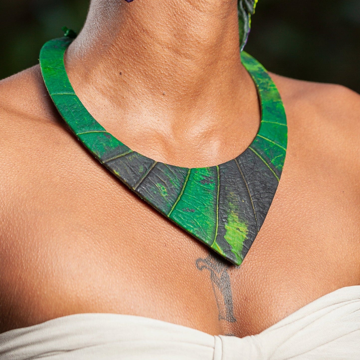 Necklace in green and black, crafted from Amazonian rubber and açaí seed fiber, draped on a model for a natural, bold look.