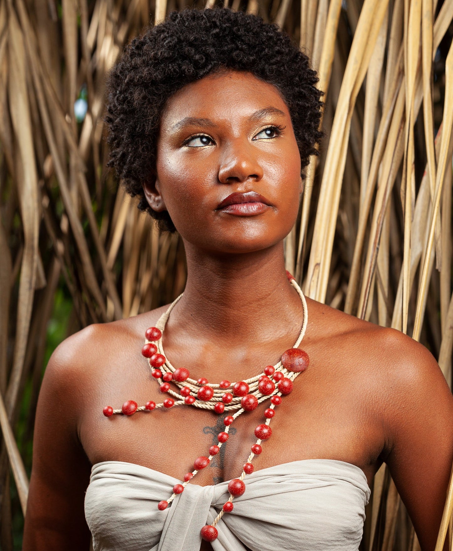 indigenous look woman wearing a red handmade necklace with Açaí seeds and Buriti fiber. 100% sustainable. 