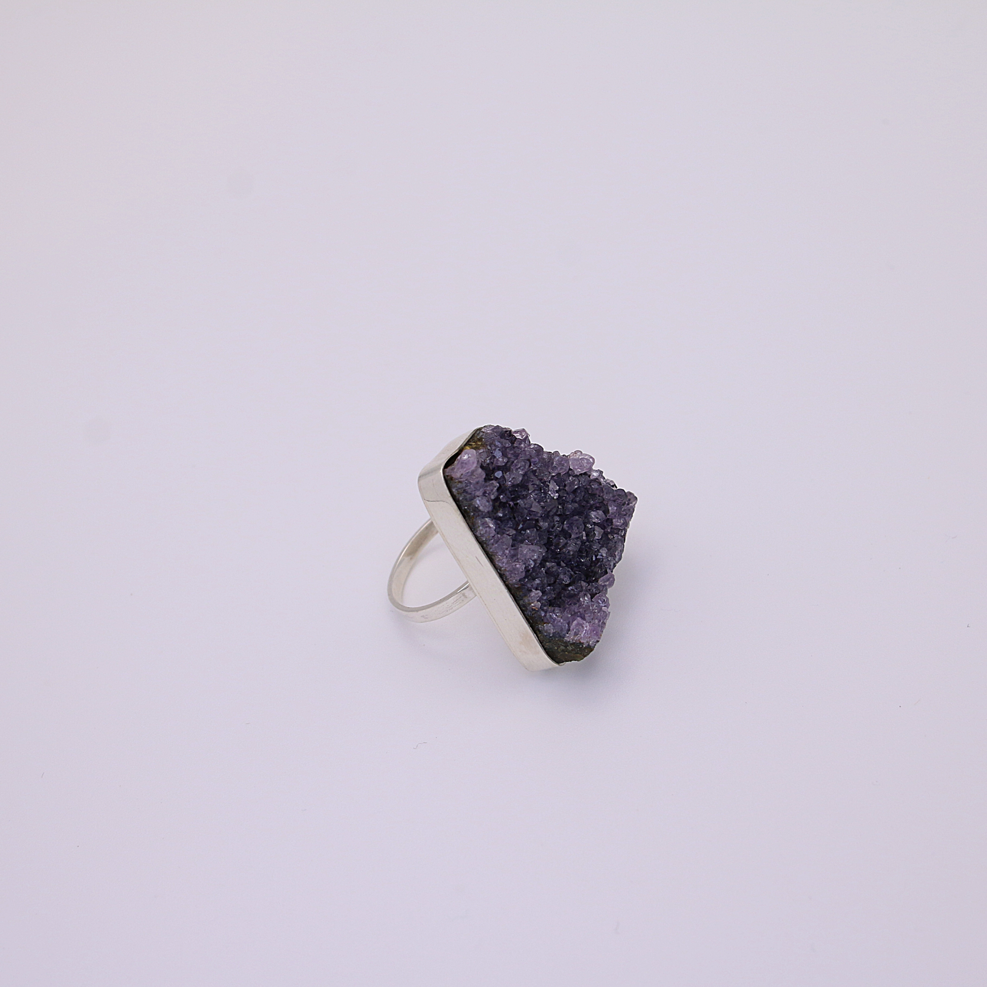 A single raw amethyst ring rests on a white background.