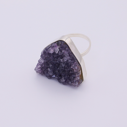 Close-up view of a raw amethyst ring with a textured surface, displayed on a contrasting white background.