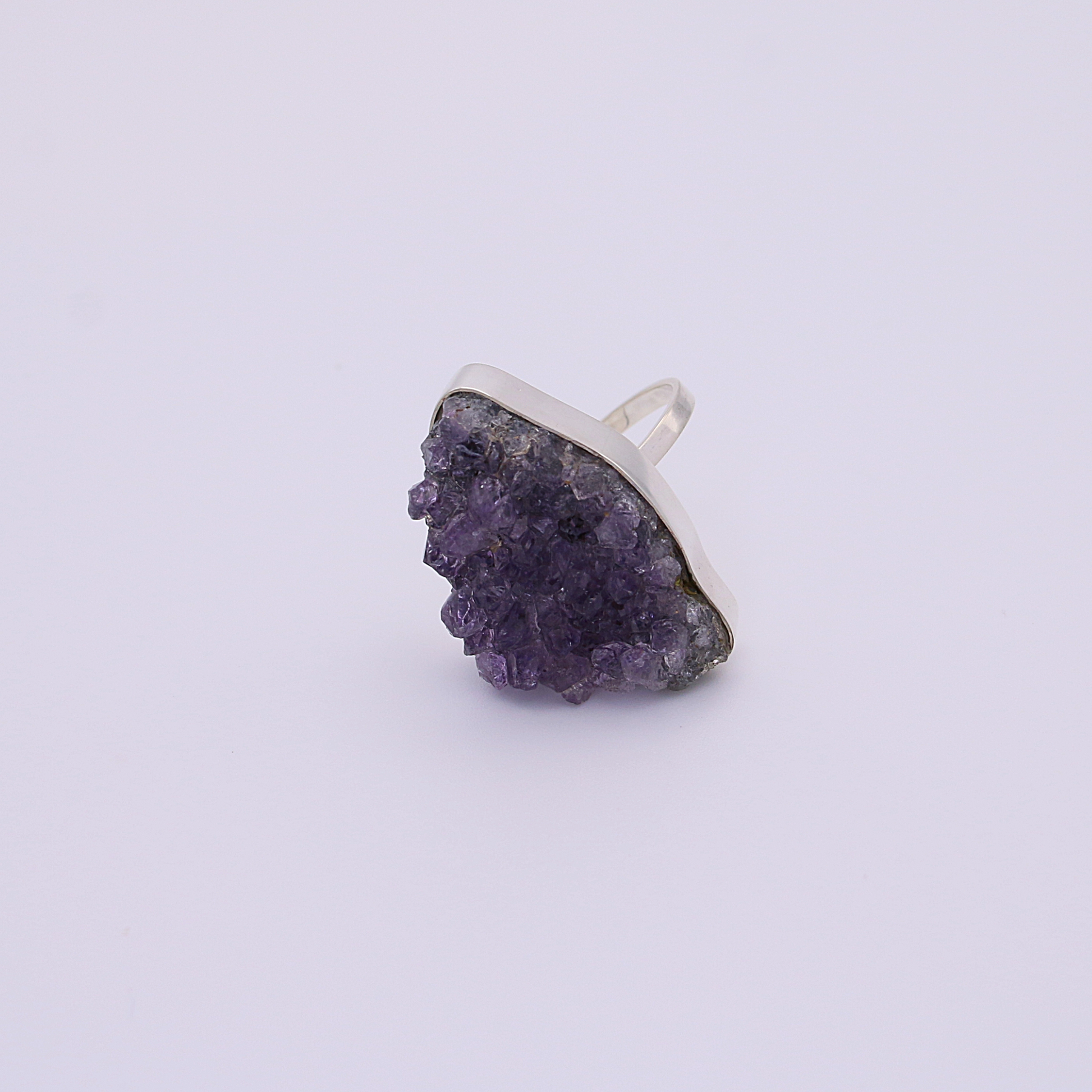  A single raw amethyst ring  on a white background, capturing the natural light.