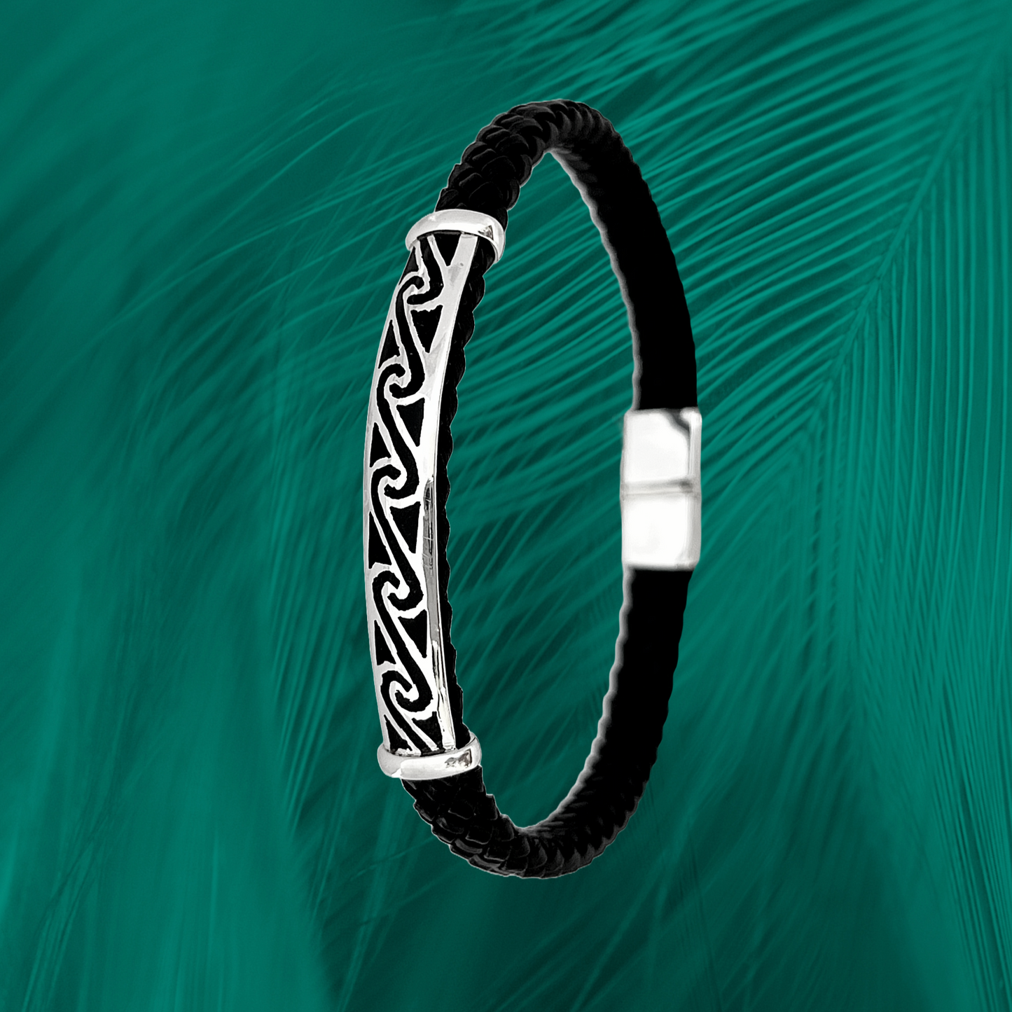 Evoking the Amazon's legendary Pororoca wave, this .925 silver bracelet features a swirling wave design. Black braided leather complements the powerful silver motif. Deep green background adds an aquatic touch.