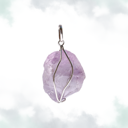  Raw amethyst pendant with a simple silver wire wrap, set against a soft, cloud-like background.