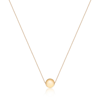 A delicate gold chain holds a polished, round gold pendant, embodying timeless sophistication and completeness.