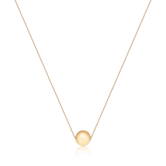 A delicate gold chain holds a polished, round gold pendant, embodying timeless sophistication and completeness.