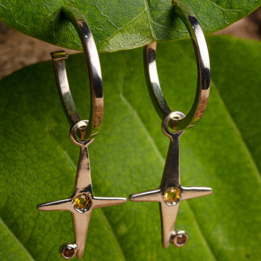 Hooped silver earrings featuring polished citrine stones at the center of star-shaped pendants, with a radiant finish to resemble sunbeams.