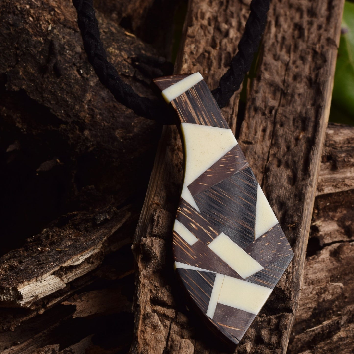 Sterling silver necklace featuring a geometric marquetry pendant. The marquetry design incorporates recycled leather, reclaimed wood, and sustainable buriti fiber.