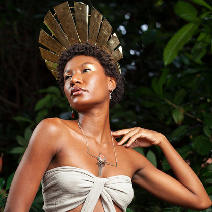 Model showcases a golden headdress, sterling silver crazy lace agate necklace & earrings, posed against lush green foliage.