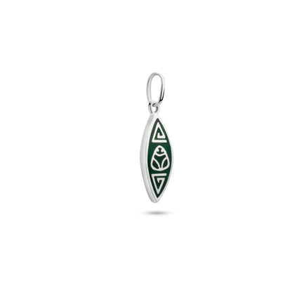 A silver pendant shaped like a stylized canoe features a green muiraquitã design, reflecting the sacred art of the Amazon's Marajoara culture, with a simple loop for attachment.