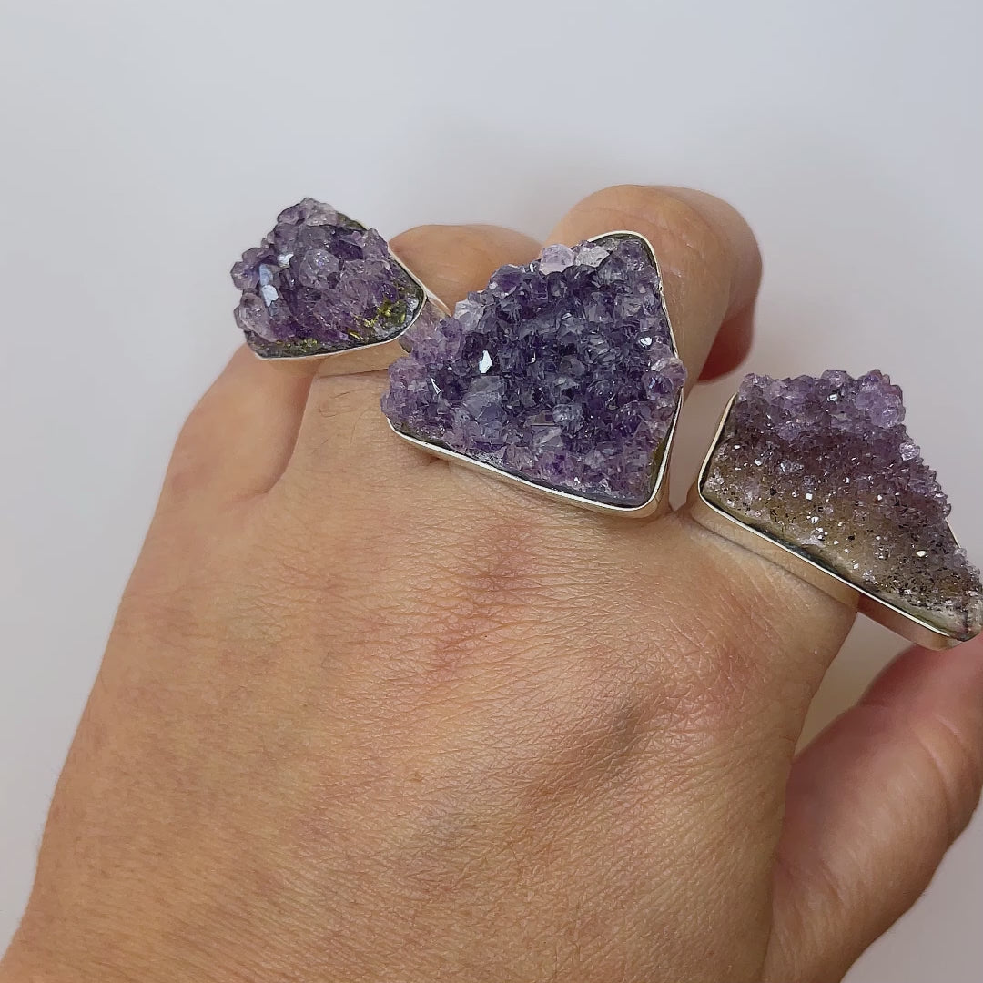 Video: Sunlight creates a dazzling sparkle on three raw amethyst silver rings worn on a moving hand.