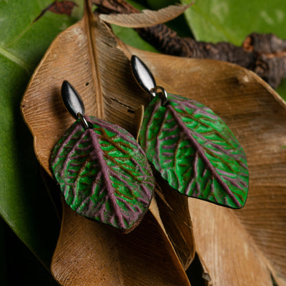 Leaf-shaped earrings handcrafted from natural rubber, green and purple blended with açaí seed fiber, featuring a matte finish and subtle vein details. Nickel-free.