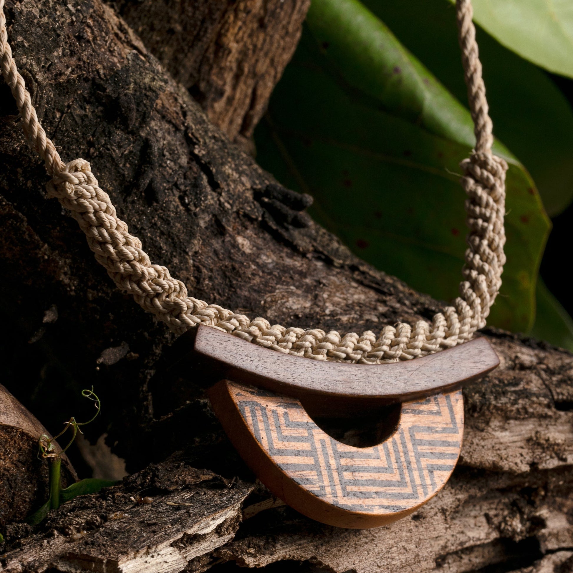 Necklace on tree bark, with buriti fiber and wood, featuring Amazonian tribal patterns as a tribute to indigenous heritage.